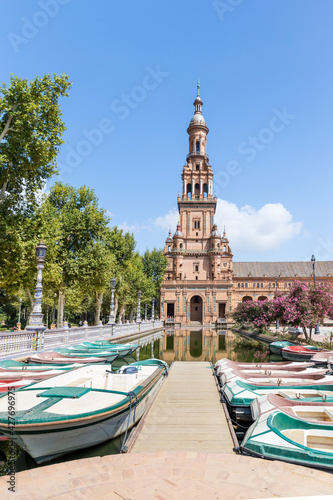Spanish Square, in the center of Seville. Very touristic travel destination empty due to coronavirus measures. View of the south tower. Boats docked. 
