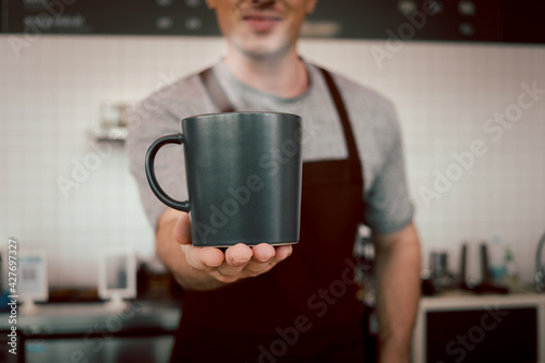 Close up of barista hands holding a cup of hot coffee in the cafe shop, waiter staff serving coffee to customer in coffee shop counter bar.