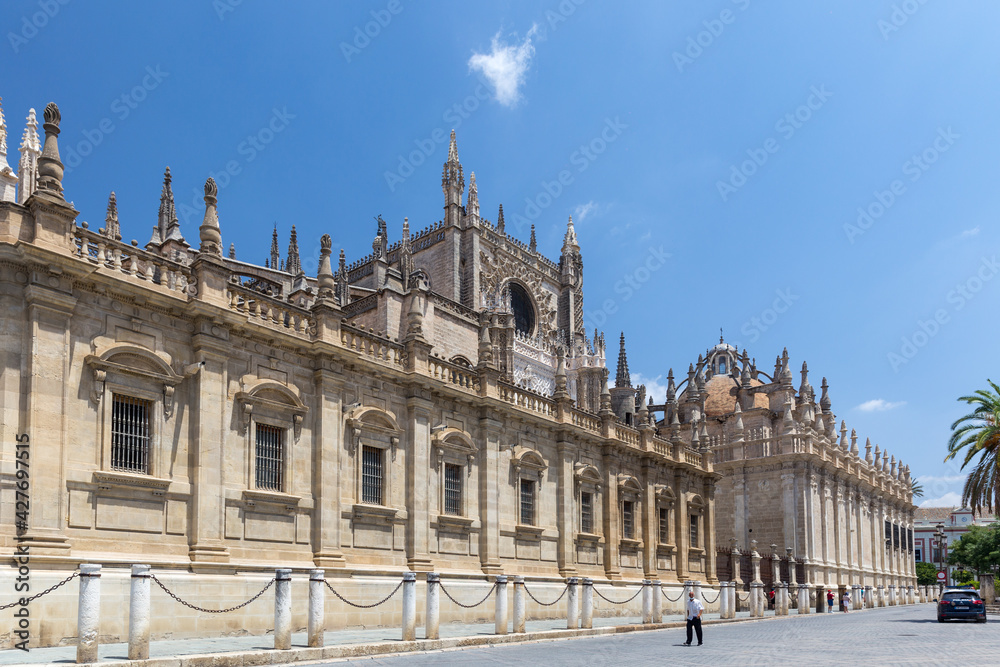 Obraz premium View of Cathedral of Seville, situated in the center of Seville. No people, blue sky red flower décor. Roman Catholic cathedral Seville, Andalusia, Spain. UNESCO 