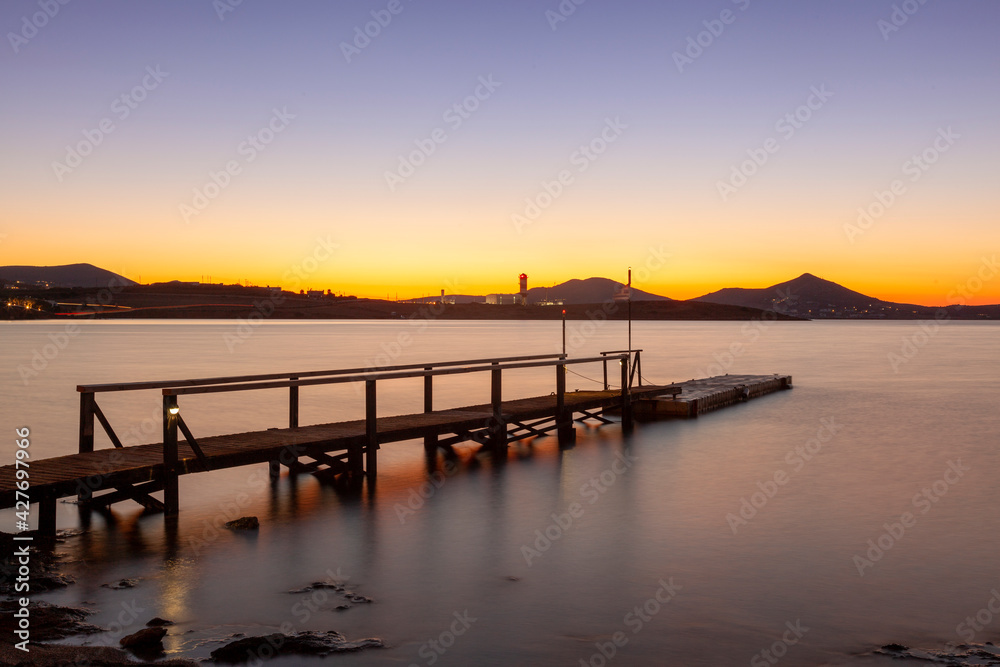 An old wooden platform as scenery of the sunset at a beach in Paros island, Cyclades islands, Aegean Sea, Greece, Europe.