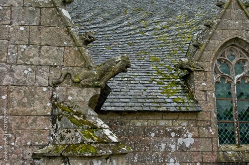 Two gargoyles worn by the elements at Plougonven Parish close in Bretagne France photo