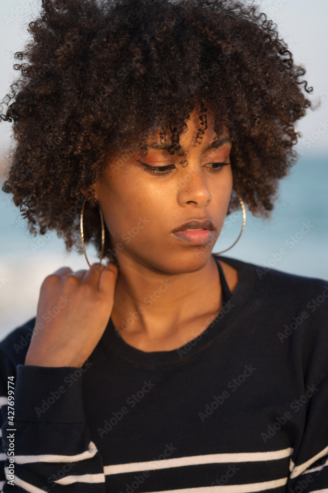 Young black woman standing by the sea wearing striped jumper Young black woman standing by the sea wearing striped jumper