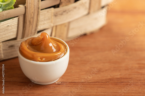 Canvas Print dulce de leche in a white container on a wooden table