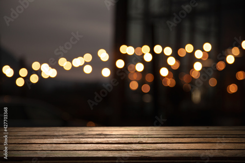 empty wooden table on blurred light gold bokeh of cafe restaurant on dark background, blurred cafe interior place for your products on the table