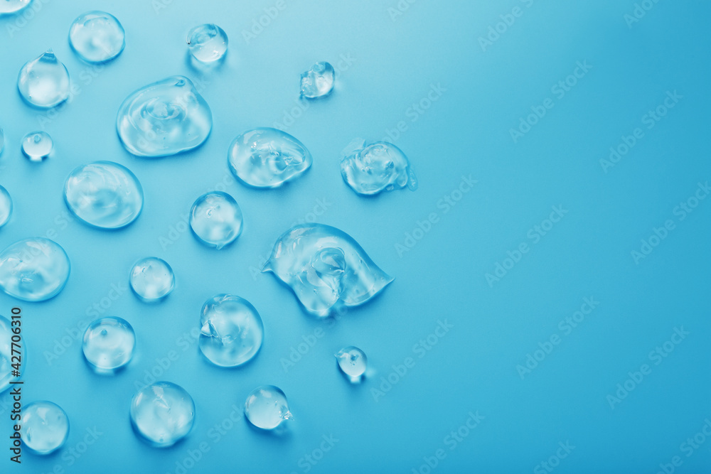 Drops of Gel with hyaluronic acid in the form of a smear of glossy texture on a blue background. Drops of Gel with hyaluronic acid in the form of a smear of glossy texture on a blue background.