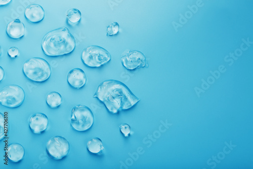 Drops of Gel with hyaluronic acid in the form of a smear of glossy texture on a blue background.