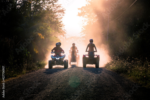Silhouette of friends driving quad bike at sunset