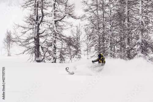 Mountain snowmobile riders ride on the slopes