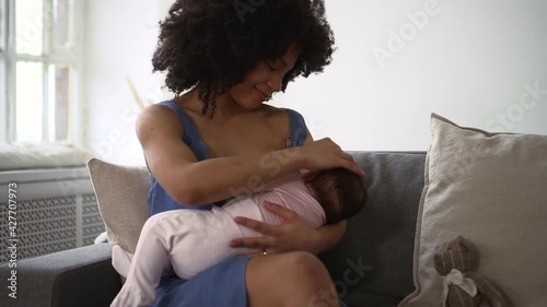Mom breastfeeding little baby and sitting on couch in apartment room spbd.