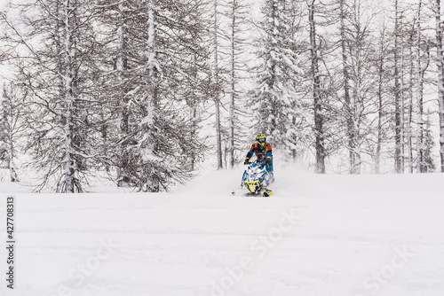 Mountain snowmobile riders ride on the slopes