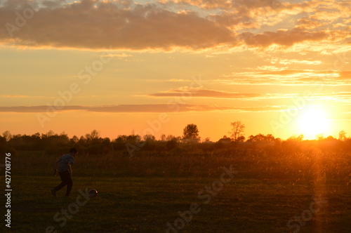 silhouette of a boy playing with a ball at sunset