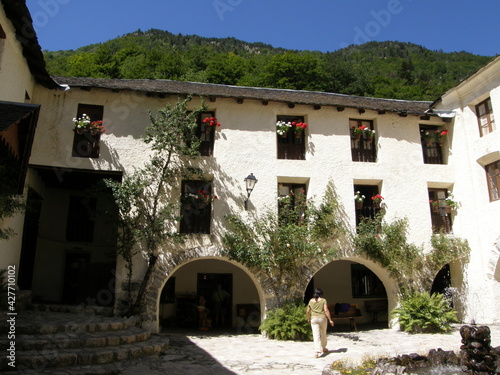 Una mujer de espaldas cruza el antiguo claustro de un convento, encalado en blanco, reconvertido actualmente en hotel-resort de montaña en los Pirineos españoles photo