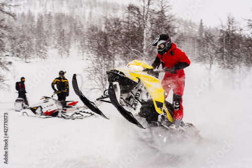 Mountain snowmobile riders ride on the slopes