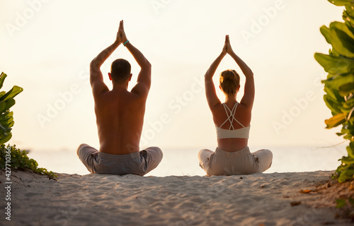 Couple meditating on sandy beach