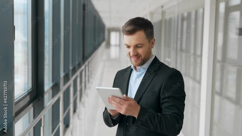 Happy young man in a glass corridor spends time with a tablet Happy young man in a glass corridor spends time with a tablet
