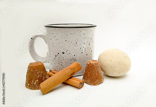 cup of atole, also known as atol, (traditional drink based on hot corn and Mesoamerican dough) and ingredients for its preparation cinnamon, dough, brown sugar photo