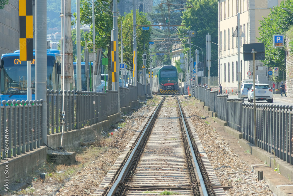 Obraz premium Un treno che viaggia sui binari in una città.