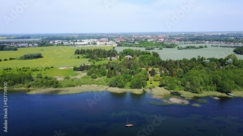 aerial view of a lake with trees, a wooden cabin and reed 