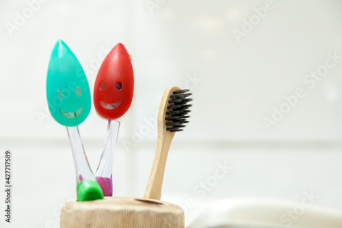 Toothbrushes from the whole family in the bathroom. Smile bristle protection brushes. All placed in the brush holder with the sink and washbasin beside it. Bathroom concept. Family concept. 