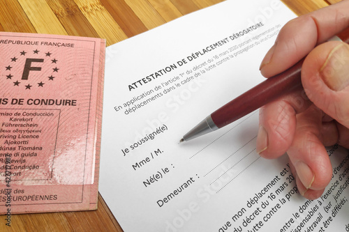 Bild auf Leinwand Close-up on a senior's hand filling an Attestation de déplacement dérogatoire that every French citizen must filled before leaving home because of the Covid-19 pandemic plan