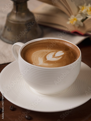 Stilllife with a Cup of coffee  cookies and a book. The atmosphere of a cozy interior Breakfast at home or in a cafe. cappuccino . latte. flowers on the wood table. candle