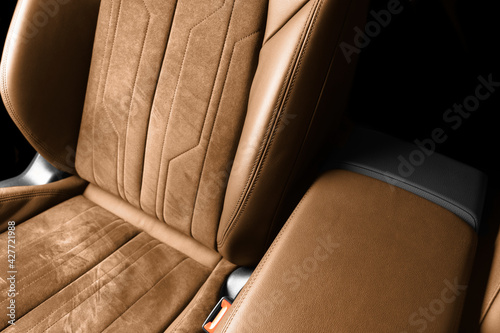 Modern luxury car brown leather with alcantara interior. Part of orange leather car seat details with white stitching. Interior of prestige car. Perforated leather seats isolated. Perforated leather. © Aleksei
