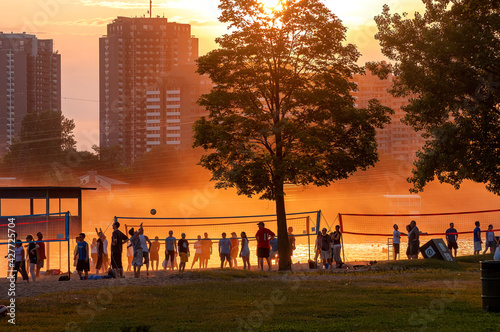 Crowd of people playing volleyball through a hot and hazy sunset