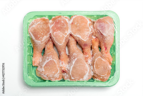 Frozen chicken meat in an open package. Chicken legs on a white background.