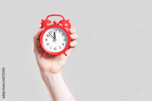 Fototapeta Naklejka Na Ścianę i Meble -  Analog red alarm clock in hand on a white background.