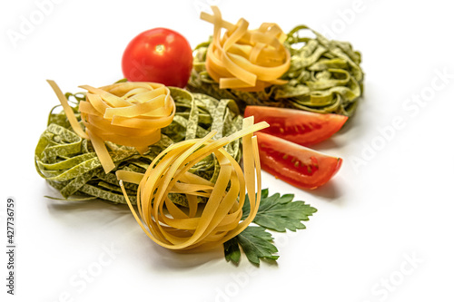 dry fettuccine pasta and tomatoes on white surface
