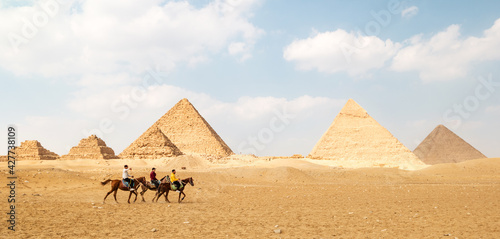 Panoramic view of Great Egyptian pyramids in Giza and three riders in front of them