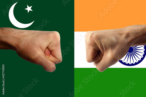 tense relations between India and Pakistan. Two fists strive for each other amid Indian and Pakistani flags