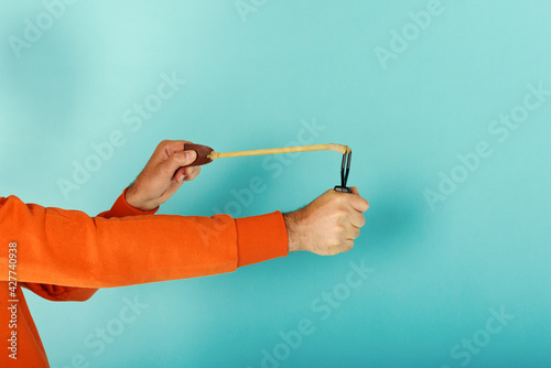 Man ready to throw from the slingshot something. cyan background