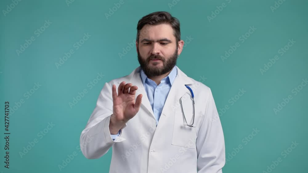 Doctor man using invisible touchscreen on blue studio background. Doc in medical coat swiping, clicking, tapping on air screen. Technology, medicine interface concept. Doctor man using invisible touchscreen on blue studio background. Doc in medical coat swiping, clicking, tapping on air screen. Technology, medicine interface concept.