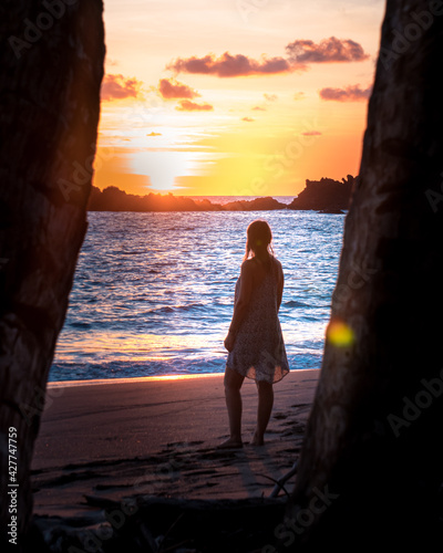 Silhouette of woman watching beautiful sunset on the beach