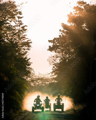 Silhouette of friends driving quad bike at sunset