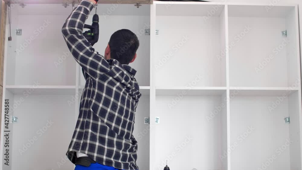 The carpenter sets the door of the kitchen shelves The carpenter sets the door of the kitchen shelves