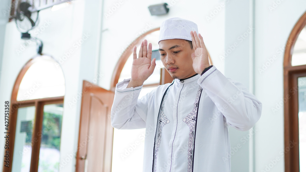 A portrait of an asian muslim man pray at mosque, the pray name is sholat, takbiratul ihram
