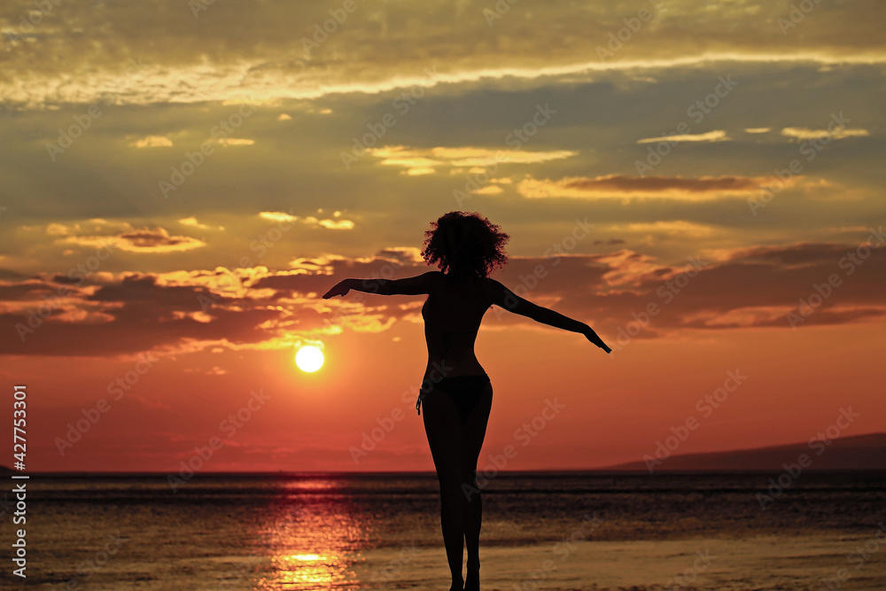 Woman silhouette on beach near sea or ocean water in evening or twilight sunset summer day on natural background.