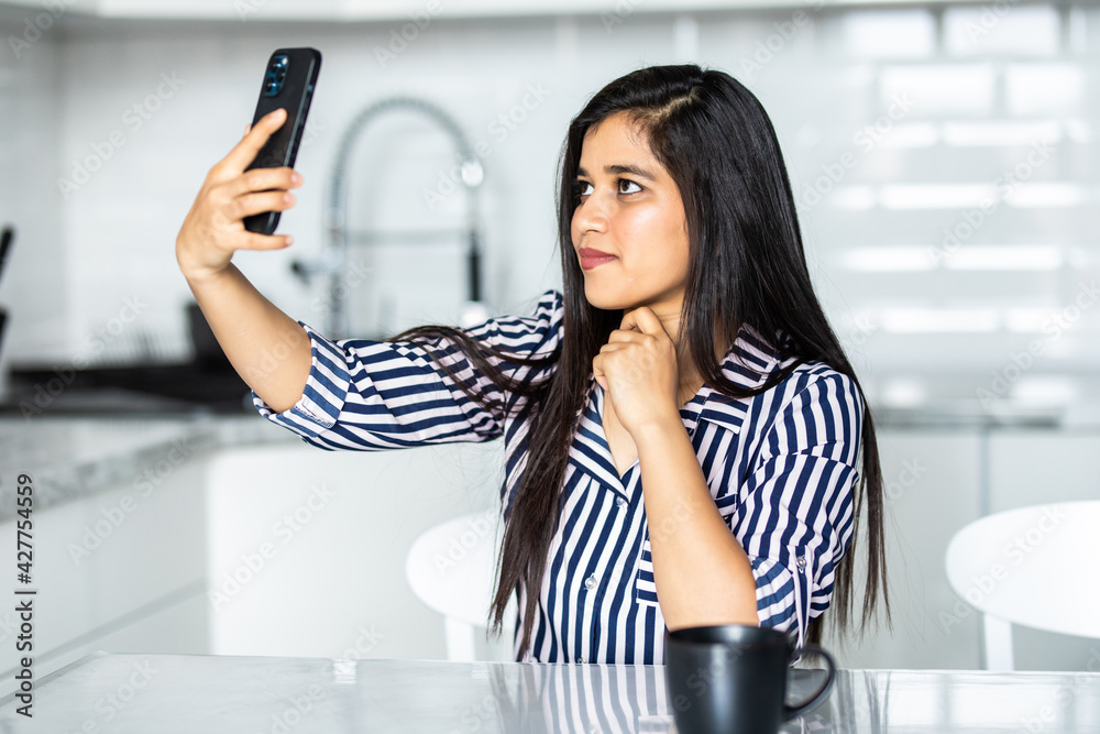 Attractive young indian woman making selfie in the kitchen. Attractive young indian woman making selfie in the kitchen.