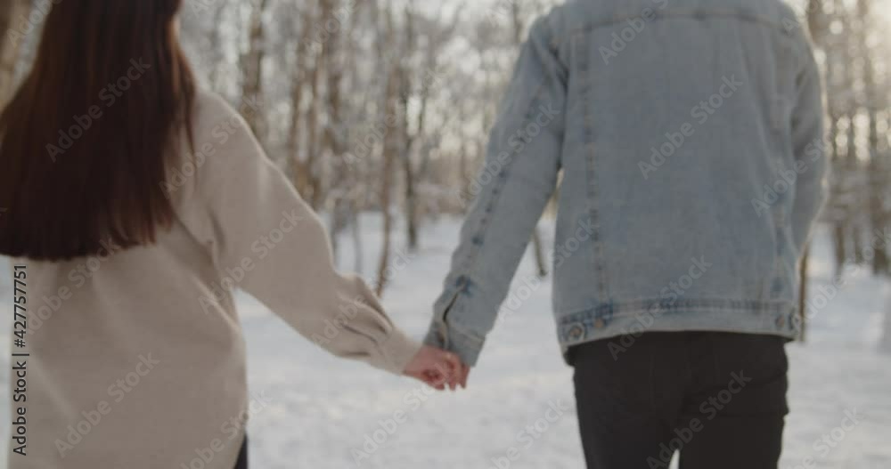 Happy young beautiful couple spend time in sunny winter forest together Happy young beautiful couple spend time in sunny winter forest together