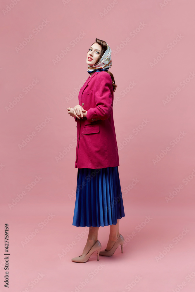 A young beautiful woman in a pink jacket and a long full-length skirt. Pin-up style. Pink background. A young beautiful woman in a pink jacket and a long full-length skirt. Pin-up style. Pink background.