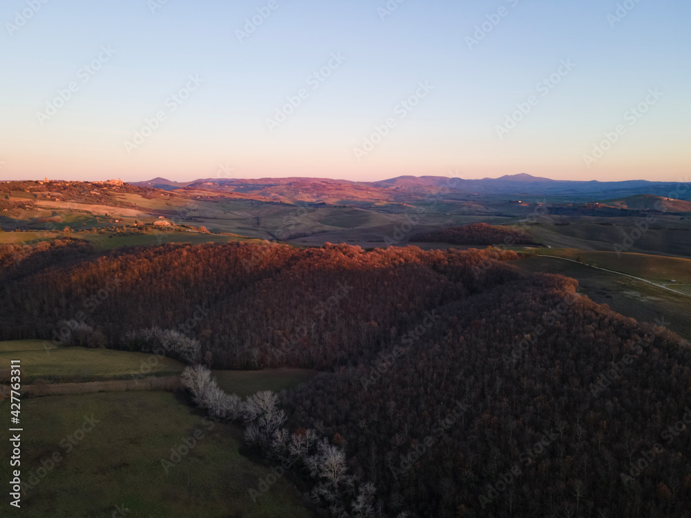 Soft colors of a sunset in Val d'Orcia Natural Area, Tuscany, Italy.  Aerial view, drone shot. 