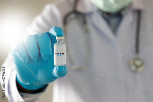 COVID-19 Vaccination, doctor holds syringe and bottle corona virus treatment vaccine