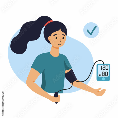 A woman measures her blood pressure with a blood pressure monitor.