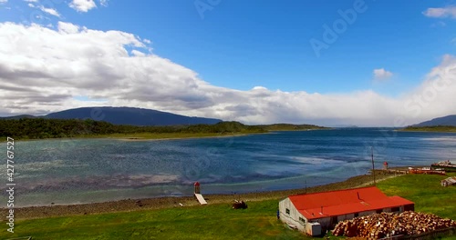 Red house and huge blue lake in Patagonia Argentina. El Chalten area with a beautiful background of mountains, rivers, trees, and blue sky. Farmhouse in south America. Drone shoot of the vast nature photo