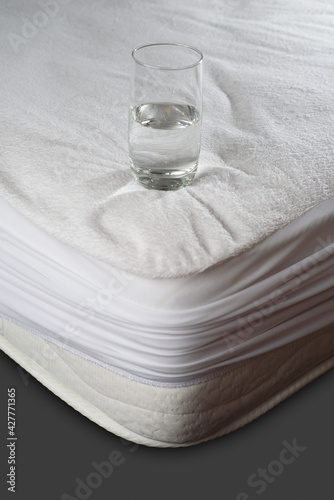 a glass of water stands on a waterproof cover on an orthopedic mattress photo