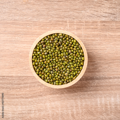 Fototapeta Naklejka Na Ścianę i Meble -  Mung bean seeds in a bowl on wooden background, Food ingredients in Asian cuisine and produce mung bean sprout