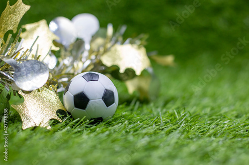 Soccer ball with Christmas Decoration on green grass for Christmas Holiday 