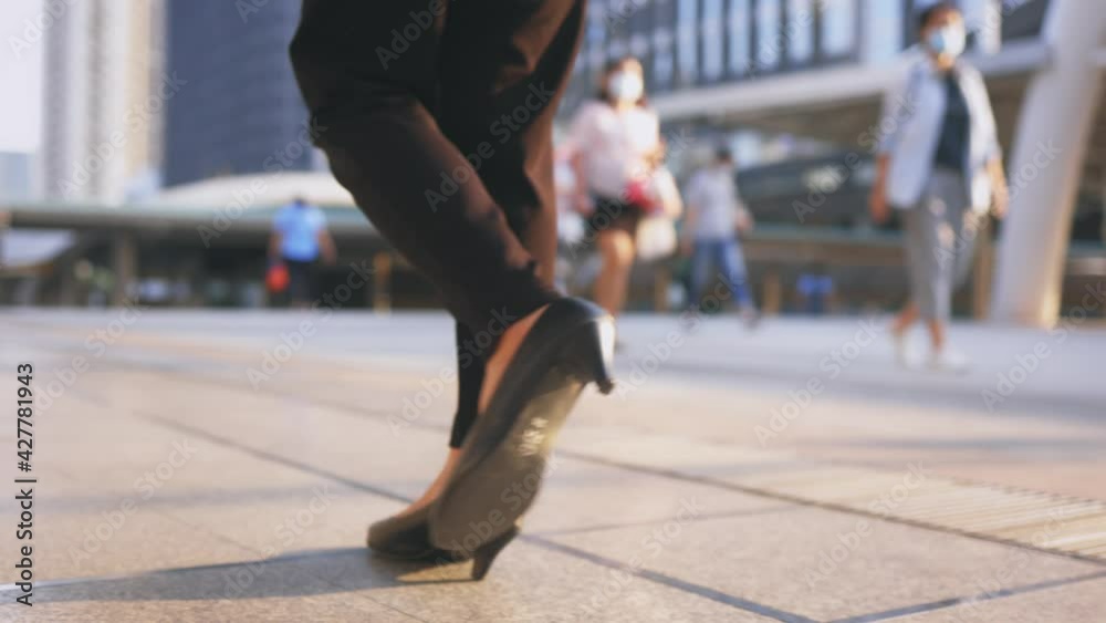 Selective focus of confident young and successful female business leader walking across business centre during daytime in formal clothing Selective focus of confident young and successful female business leader walking across business centre during daytime in formal clothing